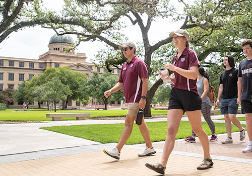 Members of the Howdy Crew lead a campus tour by the Academic Building.