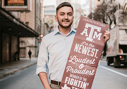 An admitted student holds a banner that reads: “Congratulations! I’m the newest, loudest, and proudest member of the fightin’ Texas Aggies!”