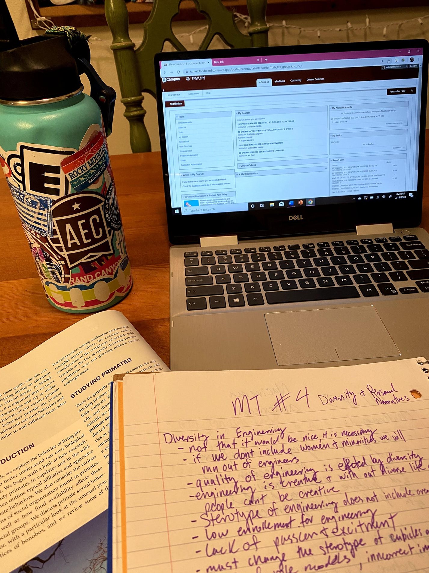 A student's desk decorated with her water bottle, laptop and notebook.