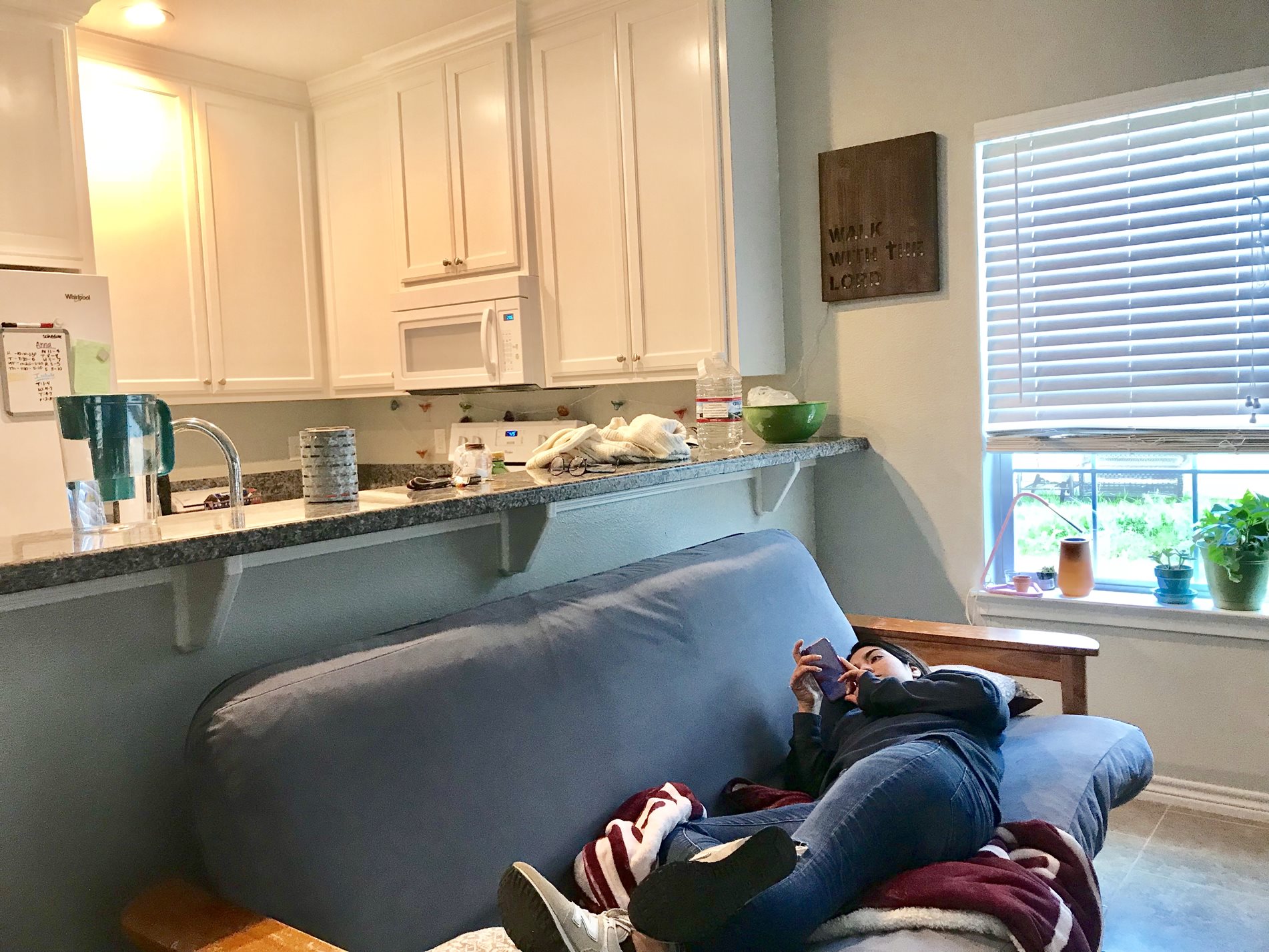 A student relaxes on their phone while laying on a couch.